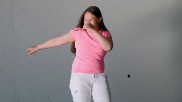 Дівчинка-підліток танцює на сірому фоні. Вуличний танець — стокове відео