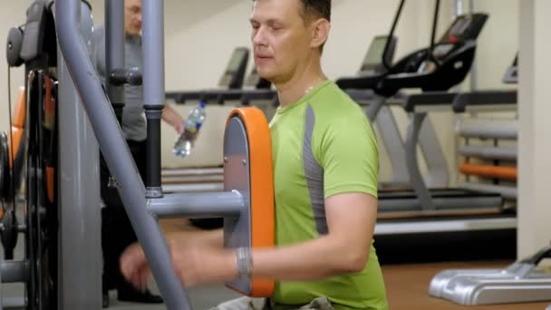 Człowiek robi ćwiczenia motyl na symulatorze w studio fitness. zdrowego stylu życia. Fitness i Sport — Wideo stockowe
