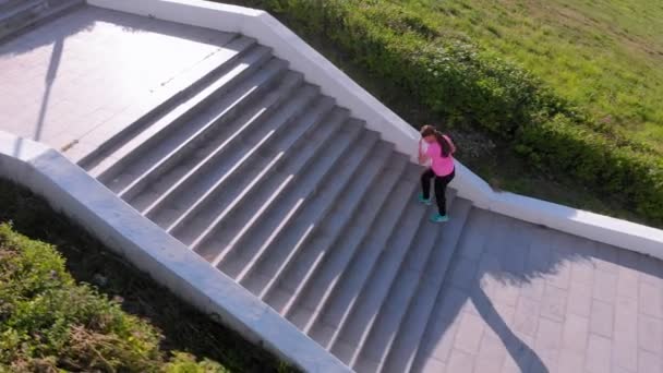 Een jong meisje loopt de trap op, sporten. Lucht schieten — Stockvideo