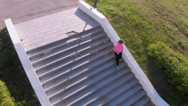 一个年轻的女孩跑上楼梯，运动。空中拍摄 — 图库视频影像