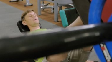 Spor salonunda simülatörde bacak presleri yapan aşırı kilolu bir adam. Fitness eğitimi. Sağlıklı yaşam tarzı kavramı