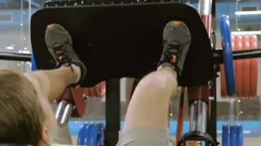 Spor salonunda simülatörde bacak presleri yapan aşırı kilolu bir adam. Fitness eğitimi. Sağlıklı yaşam tarzı kavramı