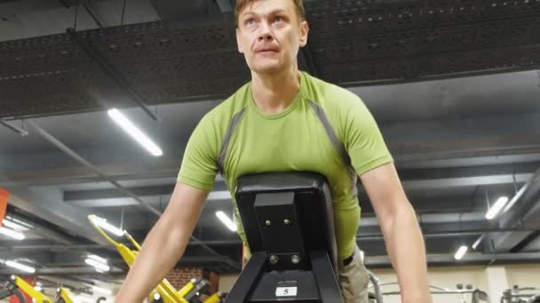 El hombre hace ejercicio en el gimnasio con simuladores. Deporte. Estilo de vida saludable — Vídeos de Stock