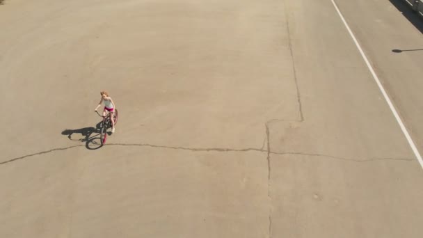 Jeune femme en vélo à l'extérieur en été. Un remblai de rivière. Transport respectueux de l'environnement. Prise de vue aérienne — Video