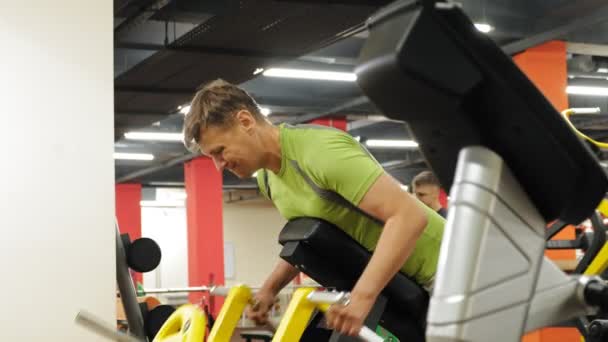 El hombre hace ejercicio en el gimnasio con simuladores. Deporte. Estilo de vida saludable — Vídeos de Stock