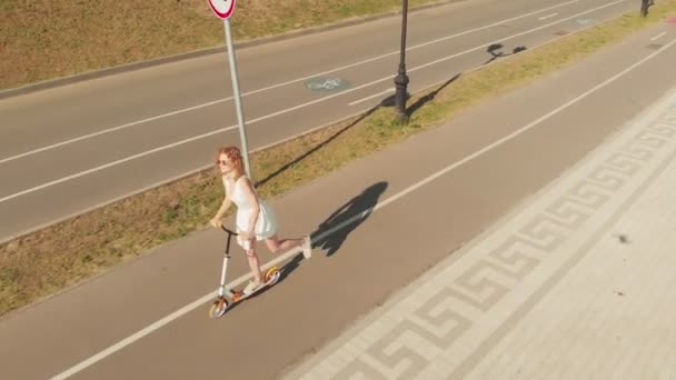Жінка катається на скутері на відкритому повітрі влітку. Повітряна стрільба — стокове відео