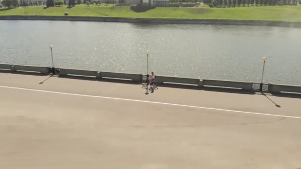 夏に屋外で自転車に乗る若い女性。川の堤防。環境に優しい輸送。空中撮影 — ストック動画