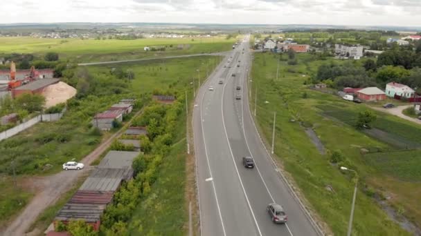 Ruch samochodów na autostradzie w pobliżu wsi. Zdjęcia lotnicze — Wideo stockowe