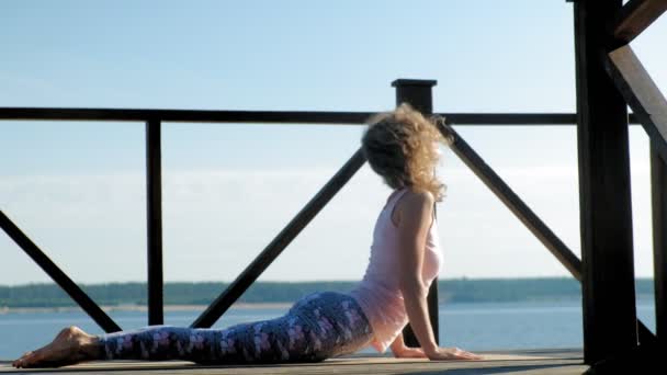 Jonge vrouw beoefenen van yoga buitenshuis in de zomer. Gezonde levensstijl — Stockvideo