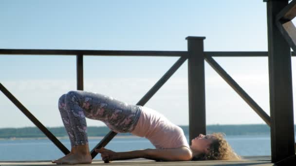 Jonge vrouw beoefenen van yoga buitenshuis in de zomer. Gezonde levensstijl — Stockvideo