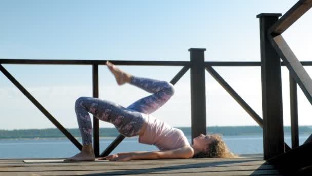 Jonge vrouw beoefenen van yoga buitenshuis in de zomer. Gezonde levensstijl — Stockvideo