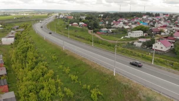 Het verkeer van auto's op de snelweg in de nabijheid van het dorp. Luchtbeelden — Stockvideo
