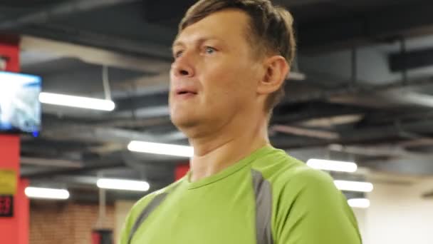Ένας υπέρβαρων άντρας σηκώνει ένα Μπάμπελ ενώ στέκεται στο γυμναστήριο. Άσκηση για δικέφαλους. Γυμναστήριο. Υγιεινός τρόπος ζωής. — Αρχείο Βίντεο