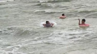 Şişme dairelerdeki insanlar denizde dalgalar üzerinde yüzerler.