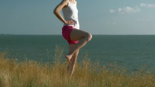 Молодая женщина занимается спортом на открытом воздухе, йогой — стоковое видео