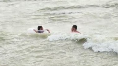 Şişme dairelerdeki insanlar denizde dalgalar üzerinde yüzerler.