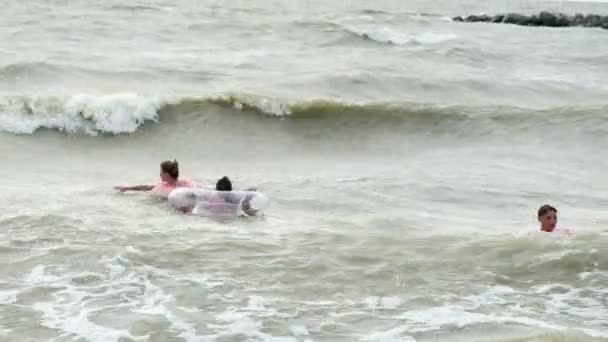 La gente en círculos inflables nada en las olas en el mar — Vídeos de Stock