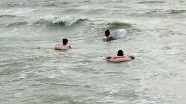 La gente en círculos inflables nada en las olas en el mar — Vídeo de stock