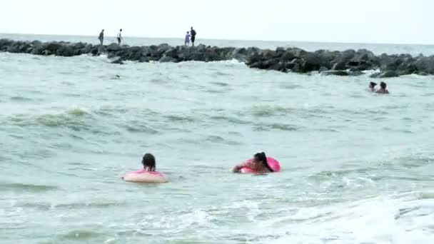 La gente en círculos inflables nada en las olas en el mar — Vídeos de Stock