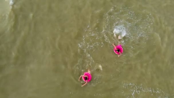 Pessoas em anéis de borracha nadam nas ondas do mar. Vídeo aéreo — Vídeo de Stock