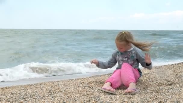 Malá holčička na mořské pláži sbírá lastury. Letní — Stock video