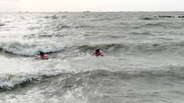 People in inflatable circles swim on the waves in the sea — Stock Video