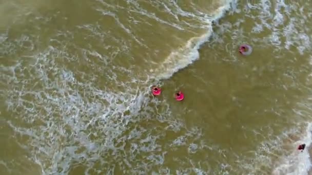 People in rubber rings swim on the waves in the sea. Aerial video — Stock Video