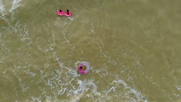 Människor i gummiringar simma på vågorna i havet. Antenn video — Stockvideo