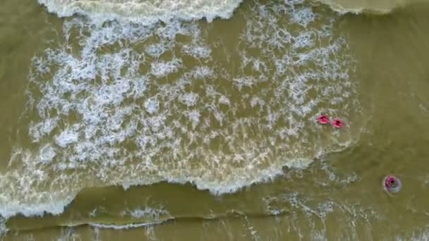 People in rubber rings swim on the waves in the sea. Aerial video — Stock Video