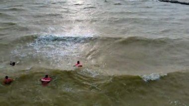Kauçuk halkalı insanlar denizde dalgalar üzerinde yüzerler. Havadan video