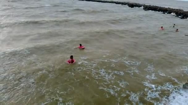 Las personas en anillos de goma nadan en las olas del mar. Vídeo aéreo — Vídeos de Stock