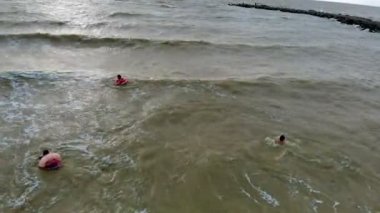 Kauçuk halkalı insanlar denizde dalgalar üzerinde yüzerler. Havadan video