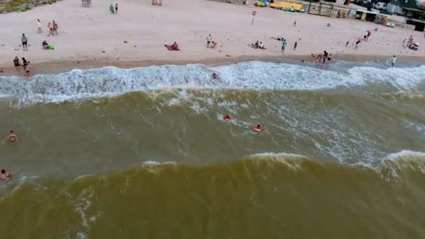 La orilla del mar al atardecer. La gente nada en el mar. Disparo aéreo — Vídeos de Stock