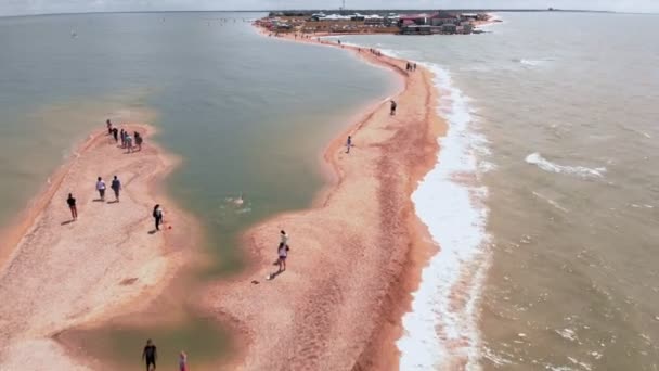 Должанская, Россия - 10 июля 2019 года: люди ходят по песчаной косе, которая уходит в море. Аэросъемка — стоковое видео