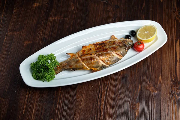 Grilled fish with a side dish and vegetables. restaurant menu