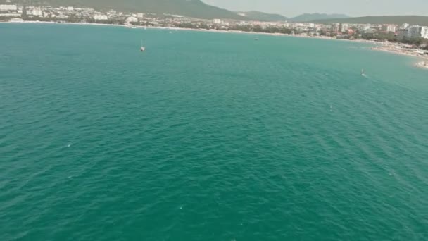 Um iate branco com uma vela flutua no mar azul no verão. Tiro aéreo — Vídeo de Stock