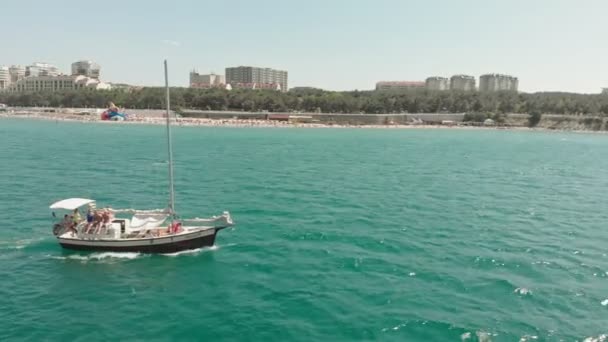 Um iate branco com uma vela flutua no mar azul no verão. Tiro aéreo — Vídeo de Stock