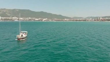 Yelkenli beyaz bir yat yazın mavi denizde yüzer. Havadan çekim