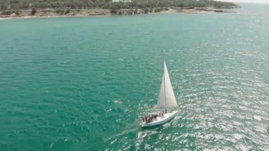 Yelkenli beyaz bir yat yazın mavi denizde yüzer. Havadan çekim