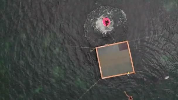 Niños alegres están saltando al mar desde una balsa. Disparo aéreo — Vídeo de stock