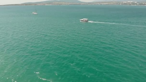 Un yate blanco con una vela flota en el mar azul en verano. Disparo aéreo — Vídeo de stock