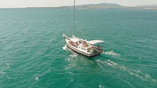 Біла яхта з вітрилом плаває на блакитному морі влітку. Повітряний постріл — стокове відео