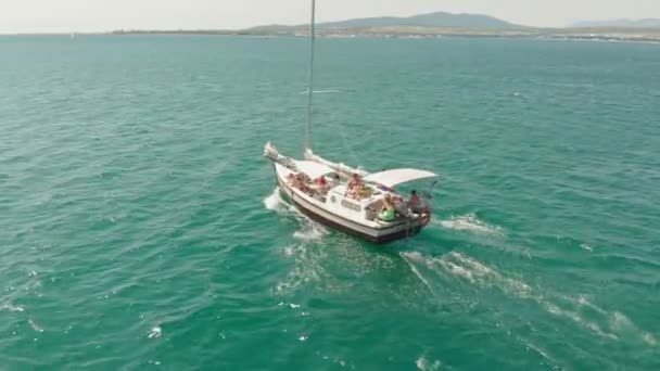 Um iate branco com uma vela flutua no mar azul no verão. Tiro aéreo — Vídeo de Stock