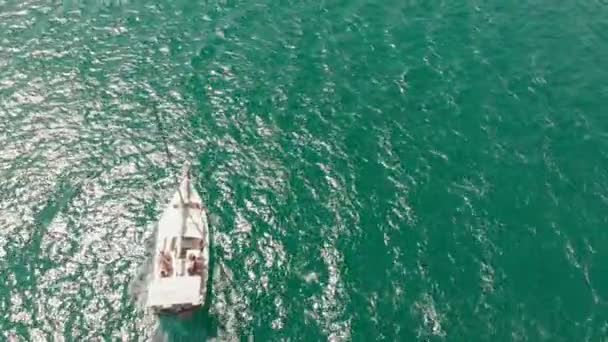 En vit Yacht med ett segel flyter i det blå havet på sommaren. Aerial shot — Stockvideo