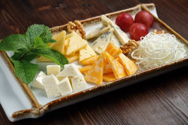 Koyu bir arka plan üzerinde peynir tabağı. Gıda stili. Restoran menüsü