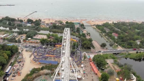 Parco divertimenti in riva al mare. Vista della ruota panoramica e del parco acquatico con drone. Sparatoria da un'altezza — Video Stock