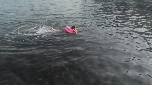 A girl floats on a rubber ring in the sea. Sea vacations in summer. Aerial shot — Stock Video