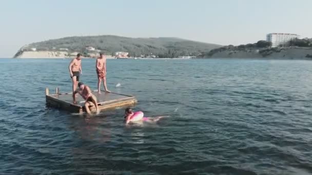 Adolescentes alegres están saltando al mar. Disparo aéreo — Vídeos de Stock