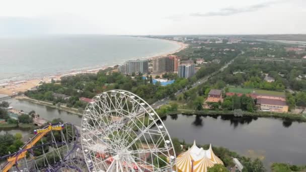 Parco divertimenti in riva al mare. Vista della ruota panoramica e del parco acquatico con drone. Sparatoria da un'altezza — Video Stock