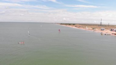 Bir adam yelkenli bir sörf tahtasında yüzer. Havadan çekim